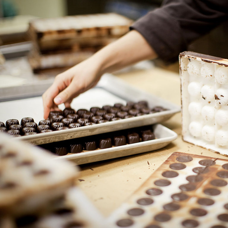 Hands emptying chocolates into a tray from the mould cavities
